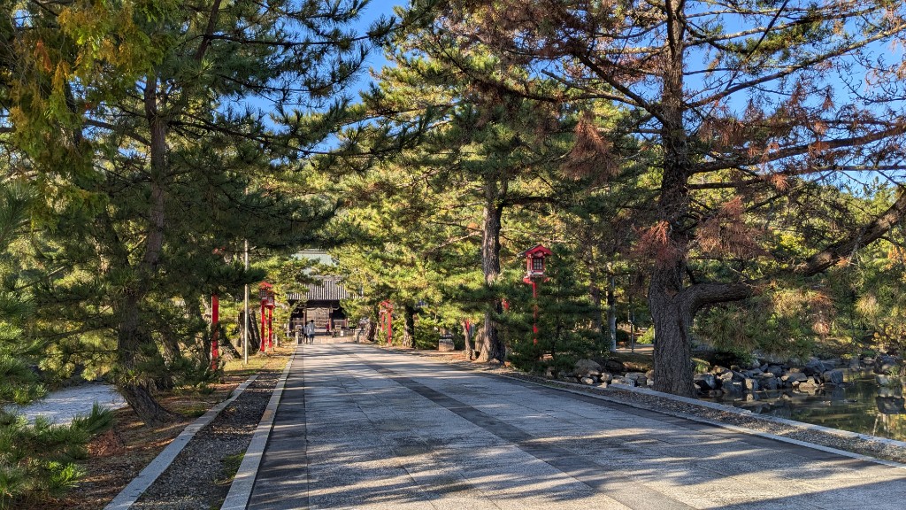 一の鳥居から随神門へと続く、風情ある吉備津彦神社の参道。両端には松の木が立ち並ぶ。